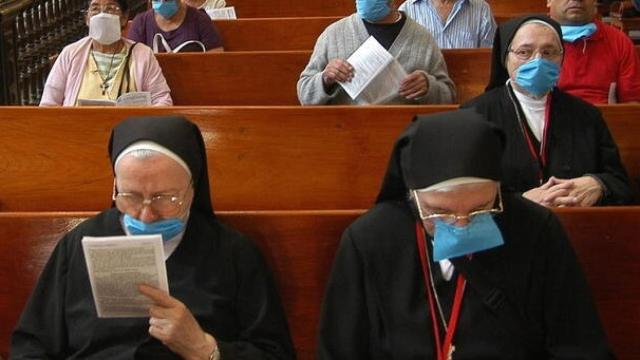 Monjas y feligreses asisten a una misa con mascarillas.
