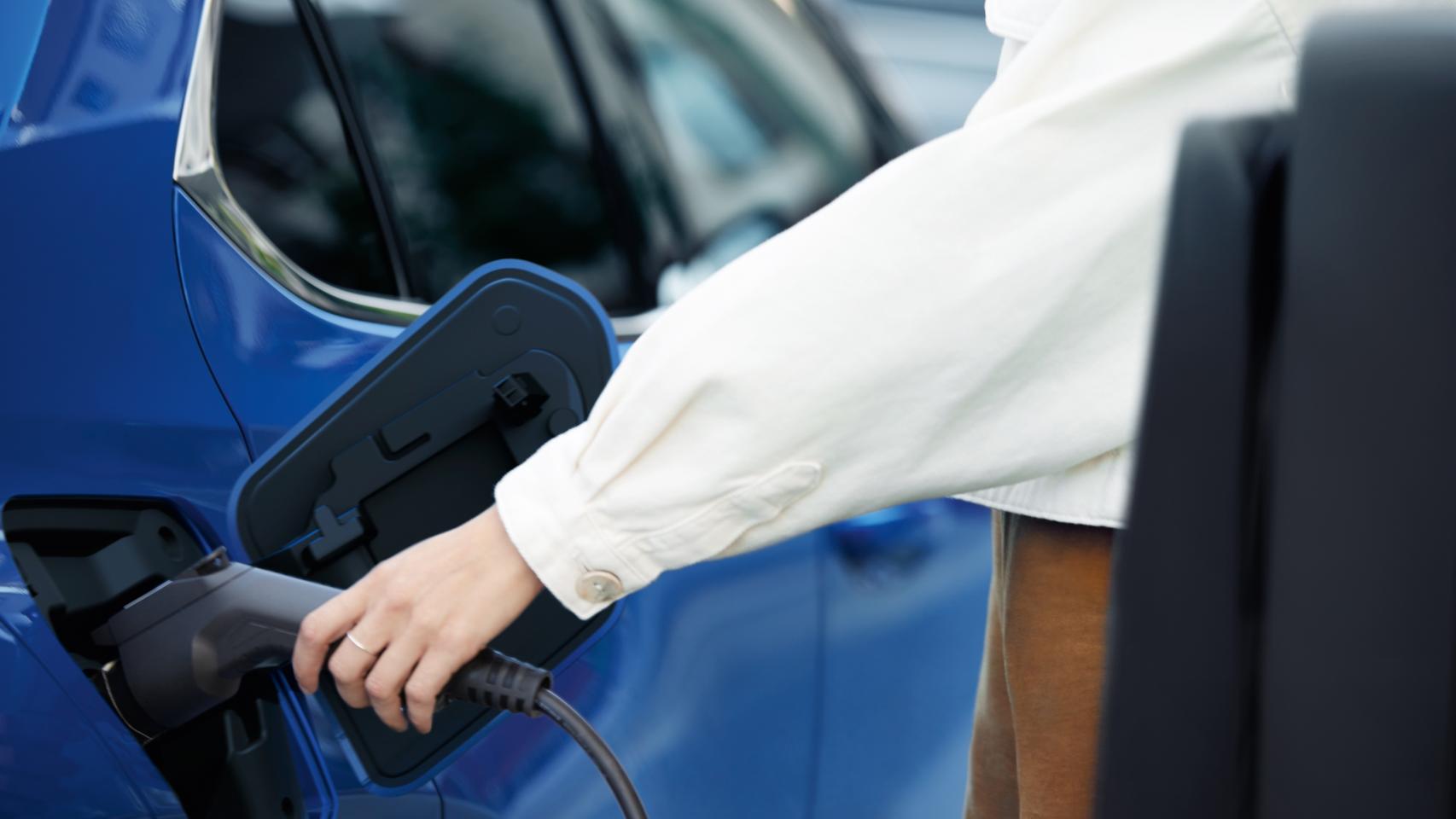 Un hombre cargando un vehículo eléctrico.