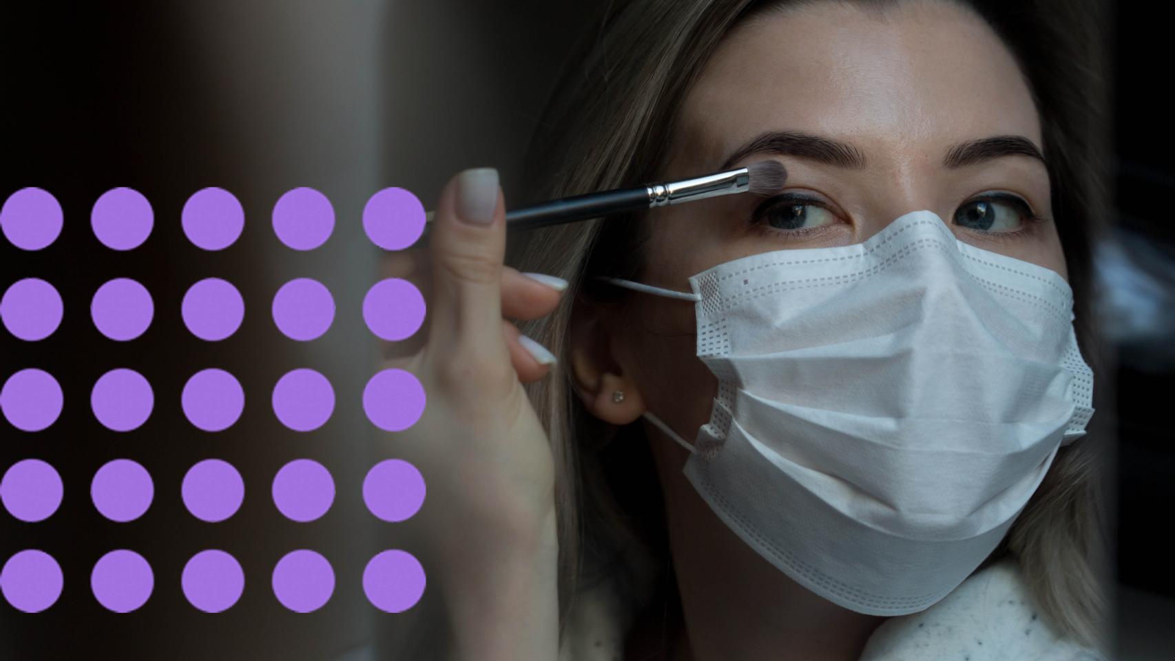 Una mujer maquillándose los ojos con la mascarilla puesta.