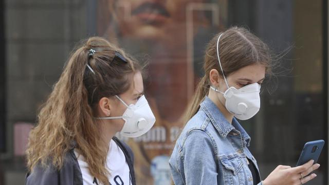 Dos jóvenes llevan mascarillas mientras pasean por la calle.