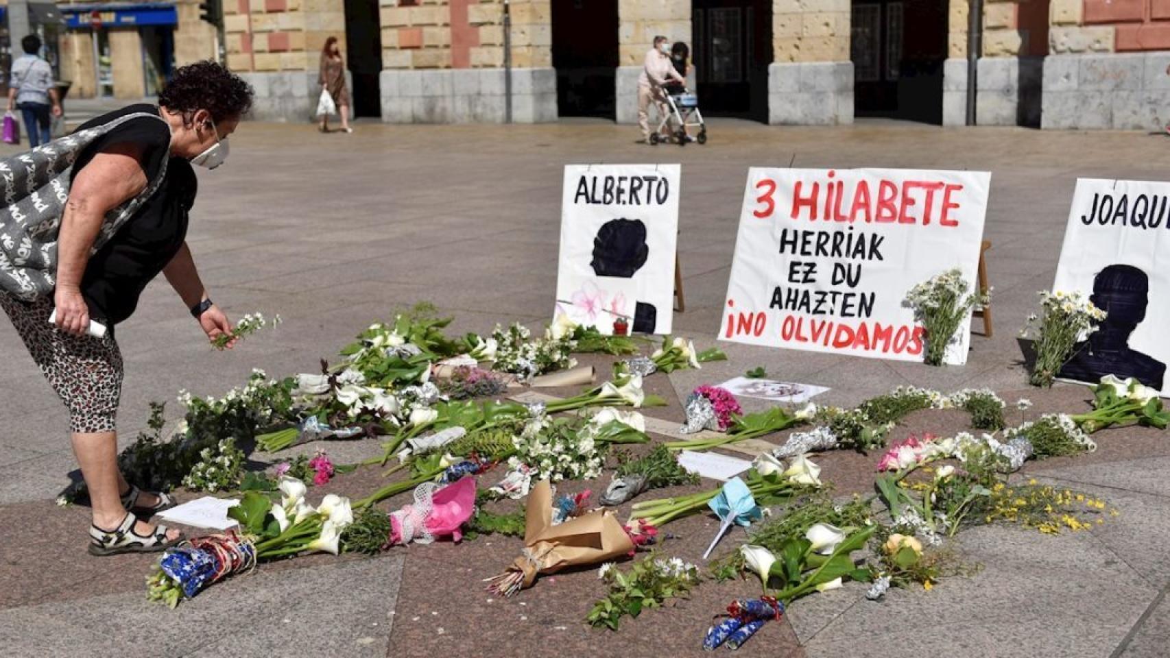 Una mujer deposita fotos en memoria de los dos trabajadores, frente al Ayuntamiento de Eibar.