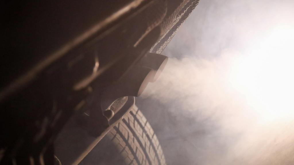 Tubo de escape de un coche emitiendo polución.