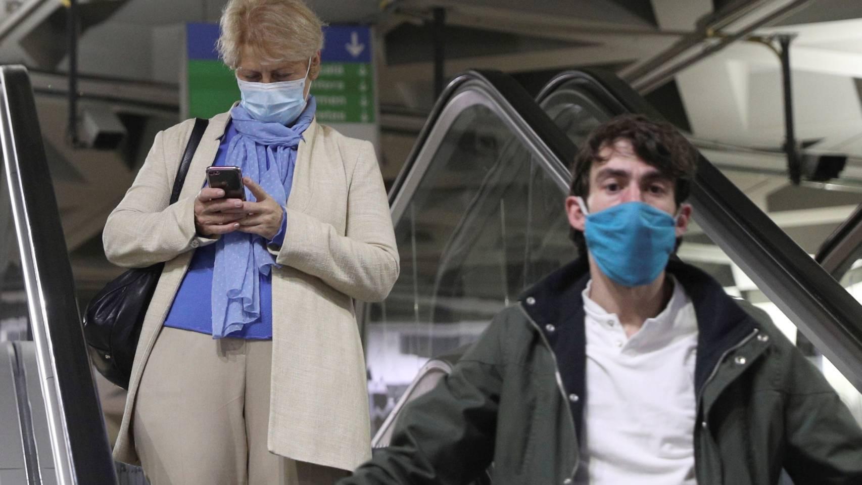 Ciudadana con mascarilla usando un móvil.