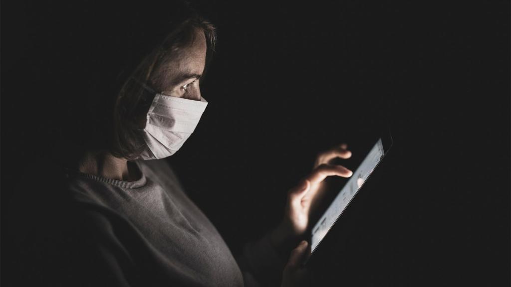 Persona usando un smartphone con mascarilla.