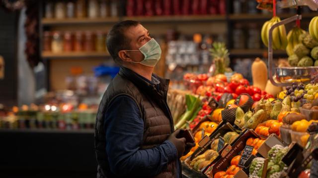 Un hombre protegido con mascarilla es atendido en una frutería.