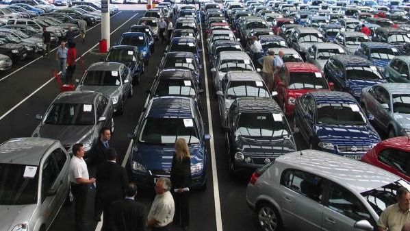 Un grupo de personas observando coches en concesionario.