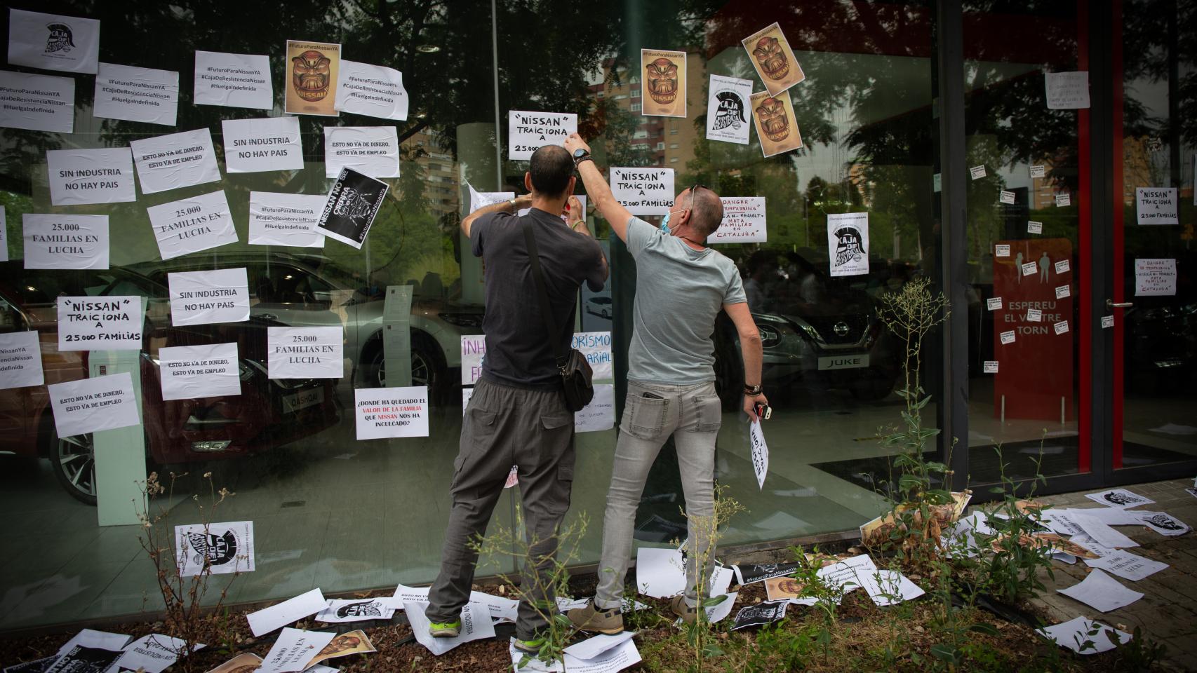 Varios trabajadores de Nissan cuelgan carteles como signo de protesta.