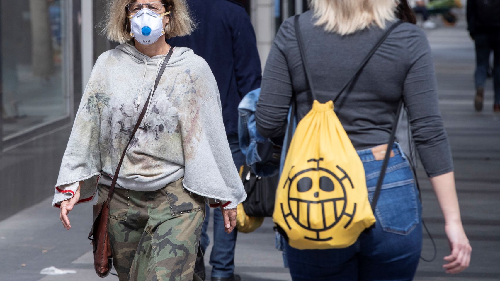 Una mujer paseando con mascarilla por la calle.