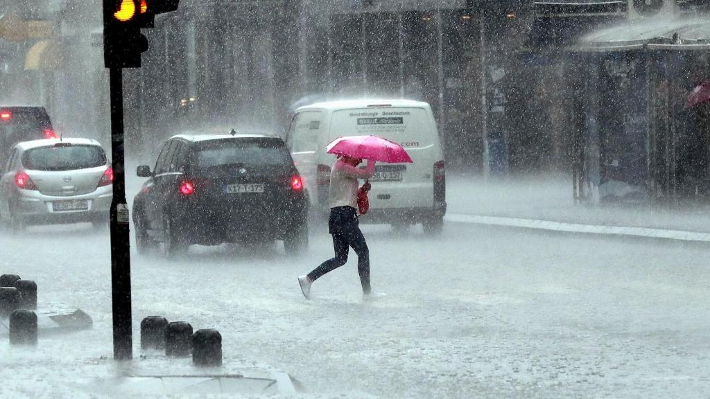Una mujer cruza la calle bajo una lluvia torrencial