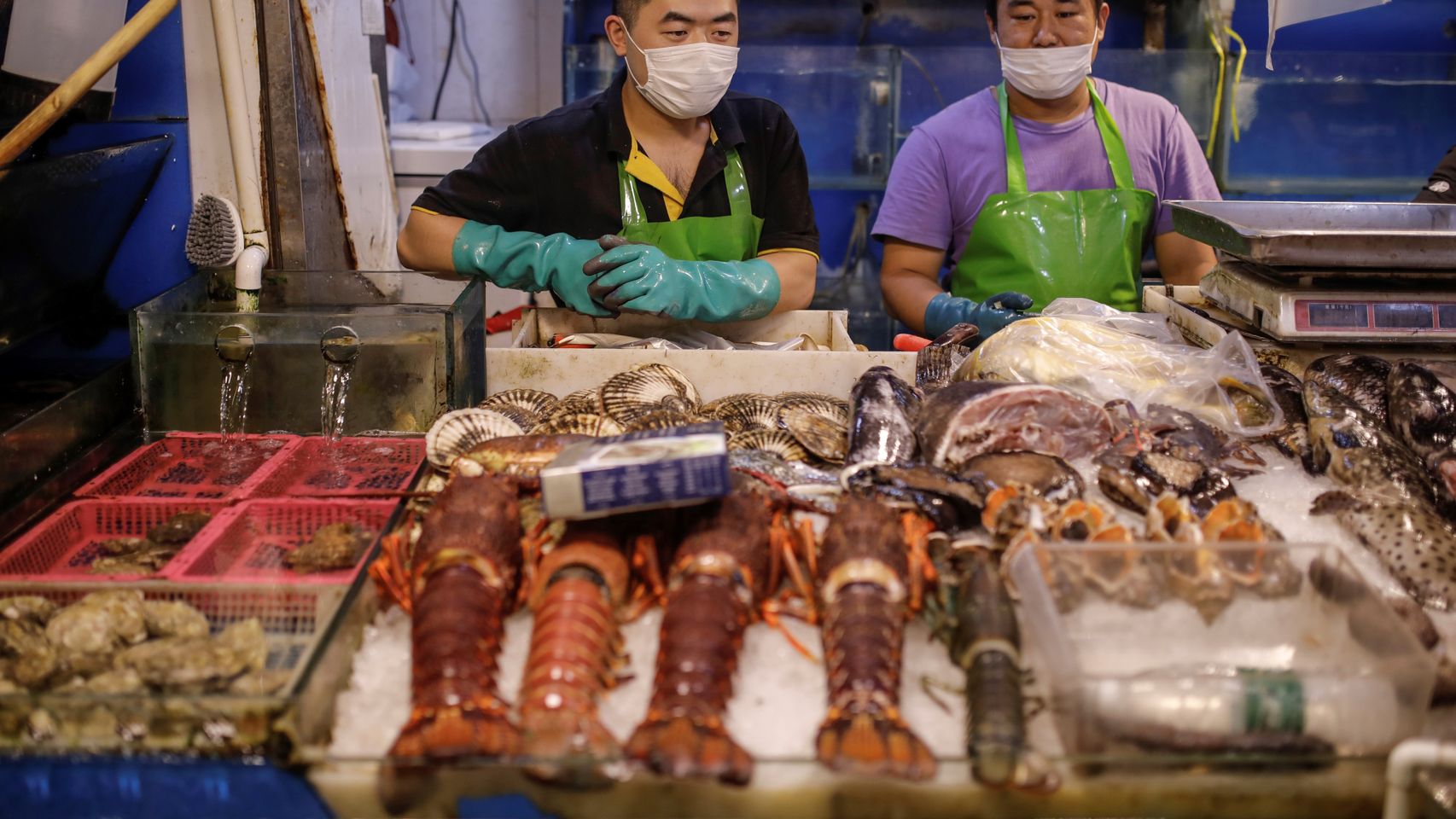 Vendedores de pescado con mascarilla en un mercado de Pekín