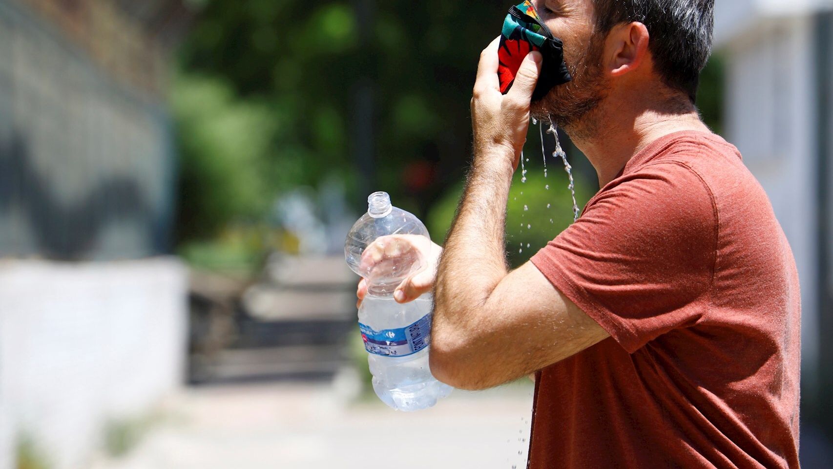 Un joven refrescándose la mascarilla contra el calor en Córdoba. EFE/Salas.