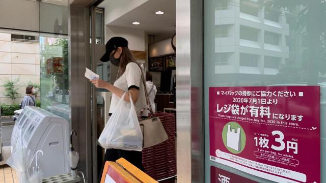 Una mujer abandona un ultramarinos en Tokio, Japón, con una bolsa de plástico desechable, este miércoles.
