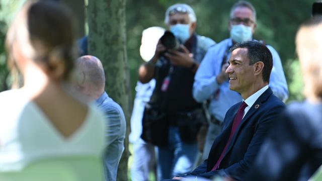 Pedro Sánchez, en los jardines de Moncloa, y la ministra Yolanda Díaz desenfocada y de espaldas.