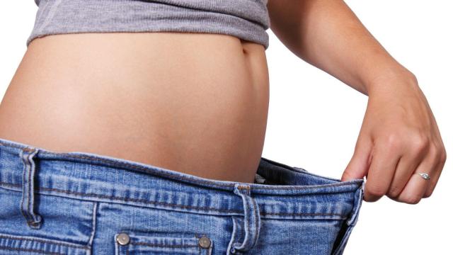 Una persona probándose sus antiguos pantalones después de una dieta.