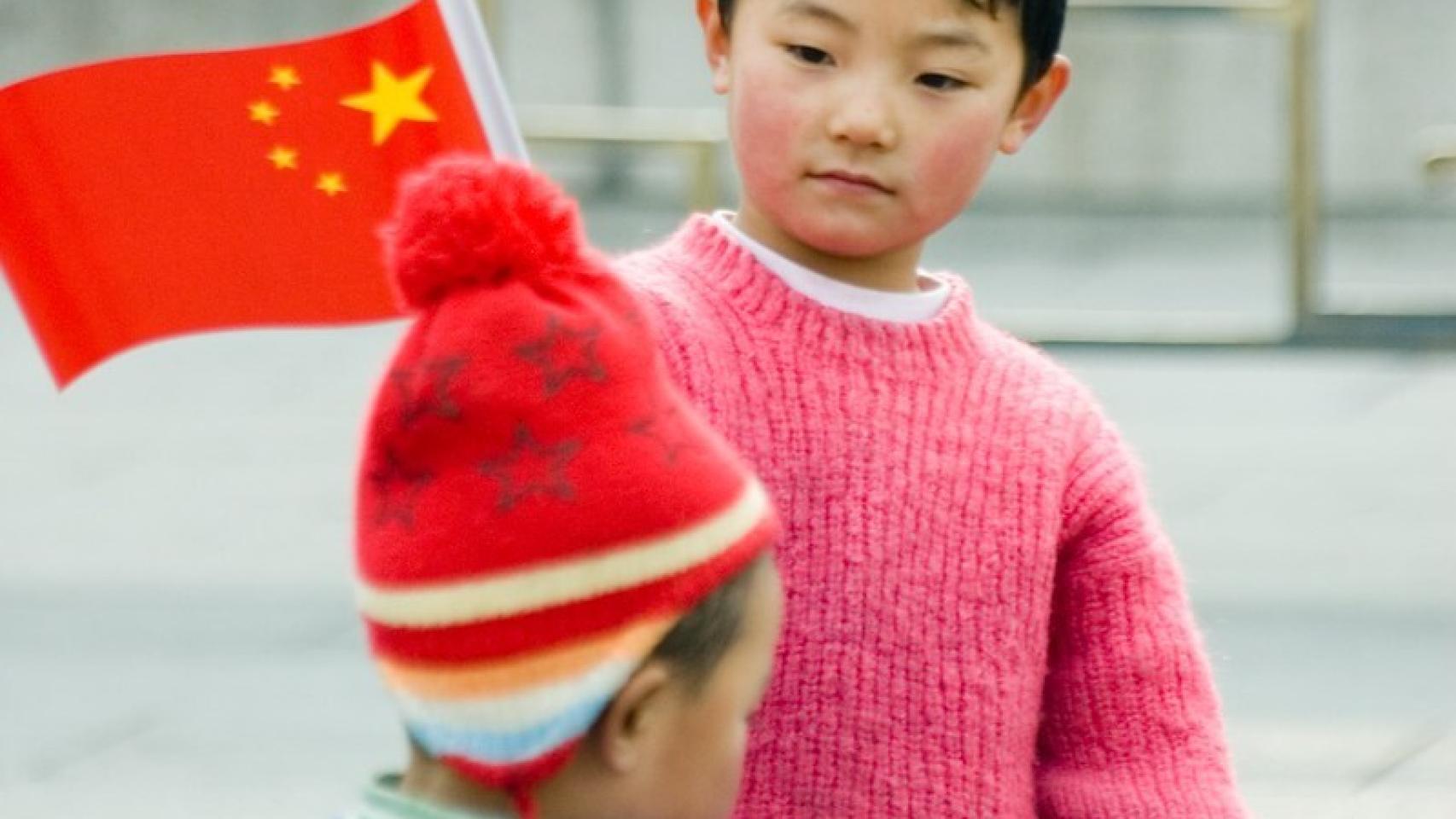 Un niño sostiene una bandera de China en Pekín.