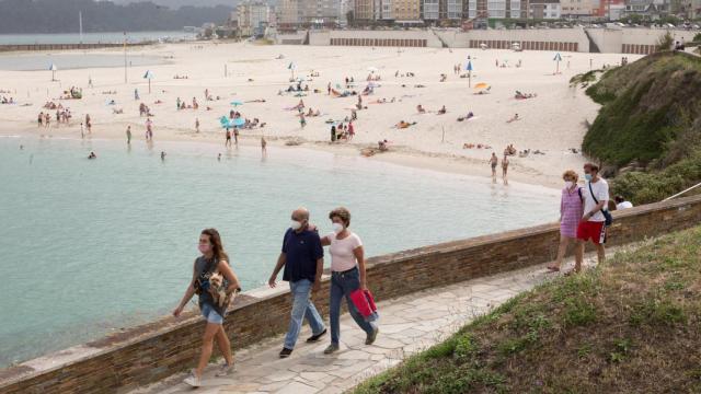 Ciudadanos pasean junto a la playa de Rapadoira de Foz, en la comarca gallega de A Mariña (Lugo).