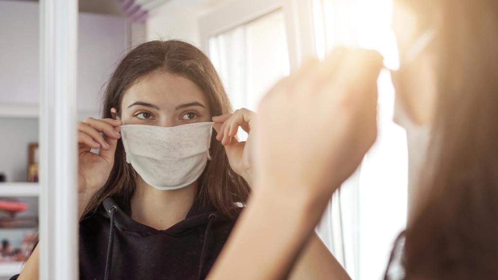 Una mujer se pone una mascarilla antes de salir de casa