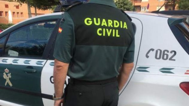Un agente de la Guardia Civil junto a su vehículo.