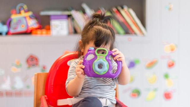 Menor con una cámara de fotos de juguete.