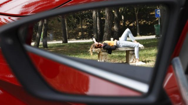 Una conductora descansa fuera de su vehículo.