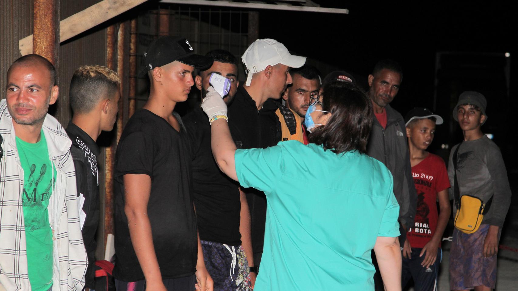 Una sanitaria toma la temperatura a un grupo de migrantes llegados a la isla de Lampedusa.