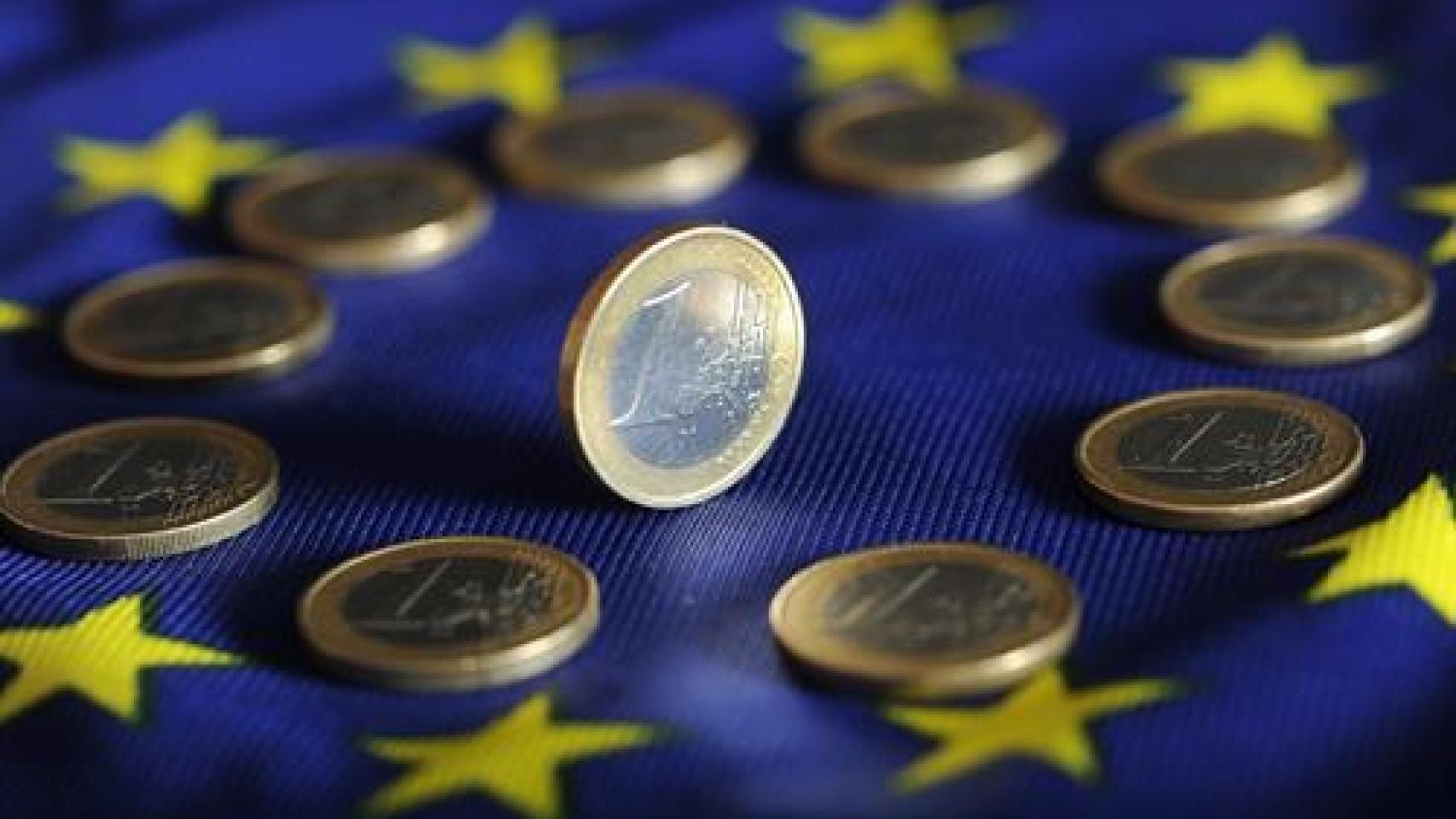 Monedas de euro sobre una bandera de la Unión Europea.