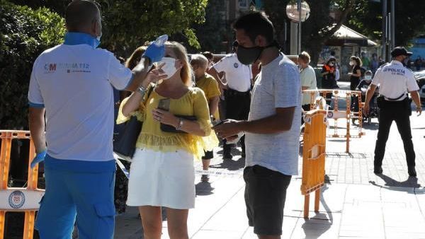 Un paramédico toma la temperatura a un mujer antes de acceder al centro de salud Reyes Católicos,  en Madrid.