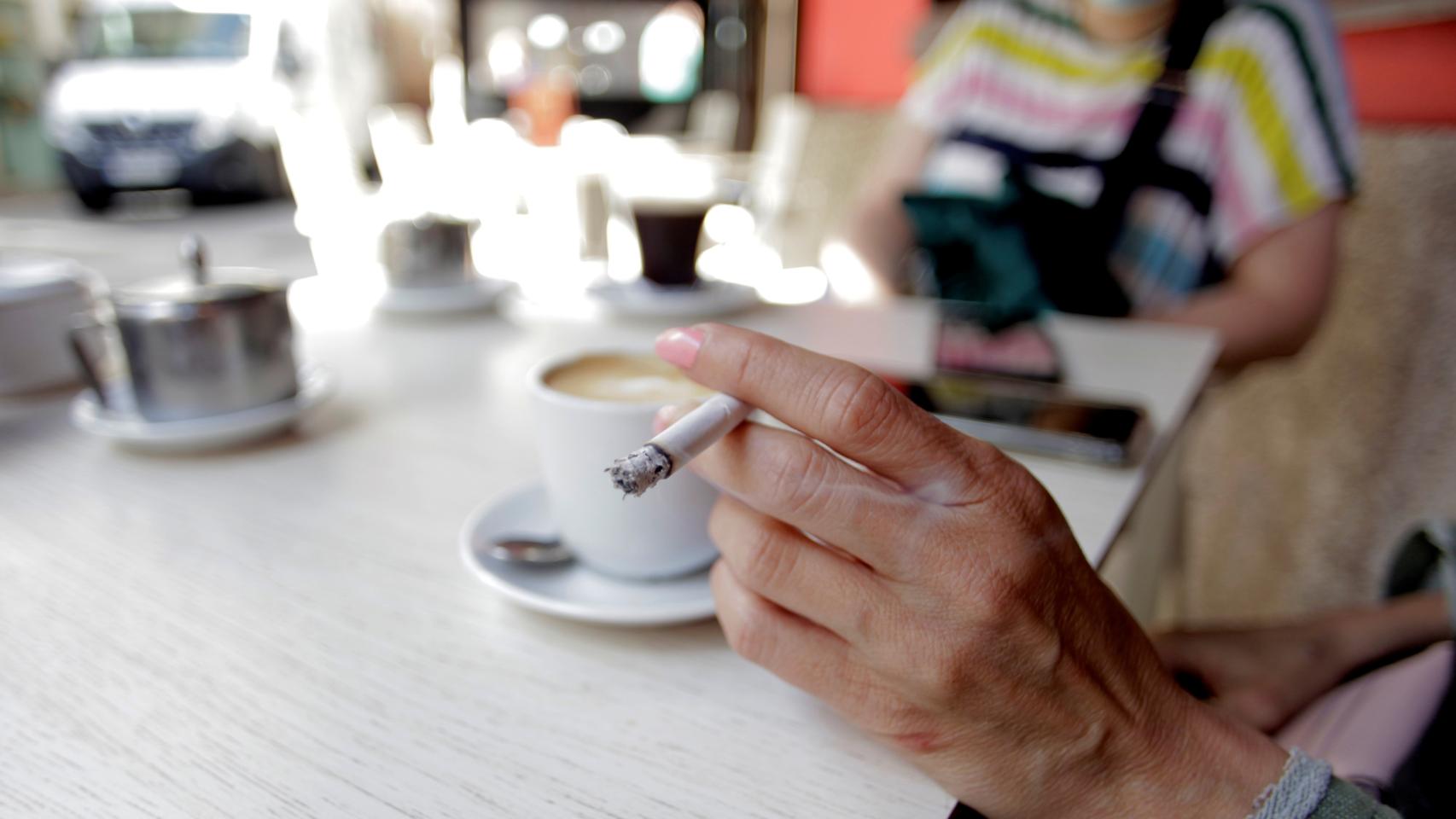 Una mujer fuma en la terraza de un bar.