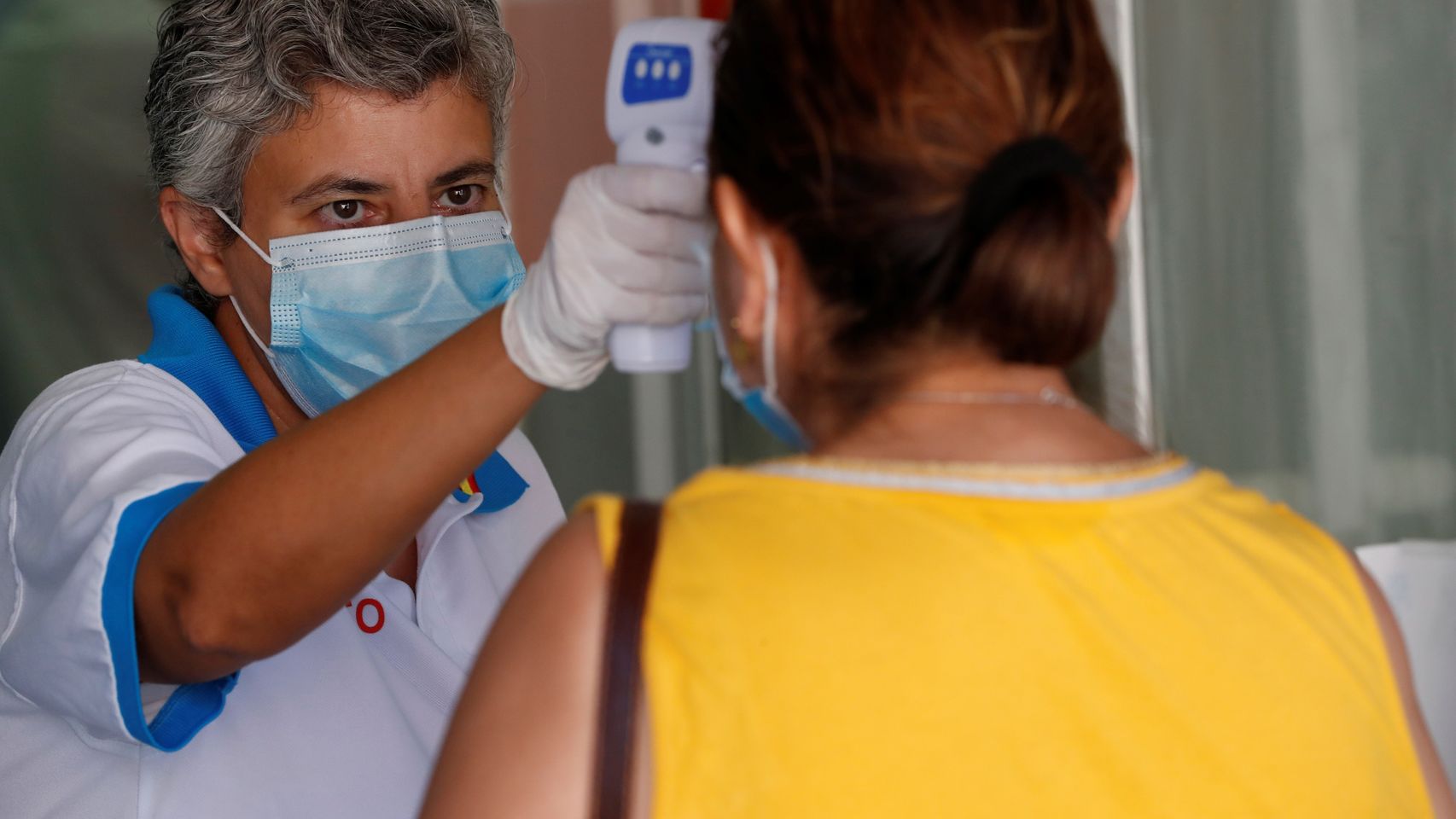 Una trabajadora de Sanidad toma la temperatura a varias personas en un hospital de Móstoles