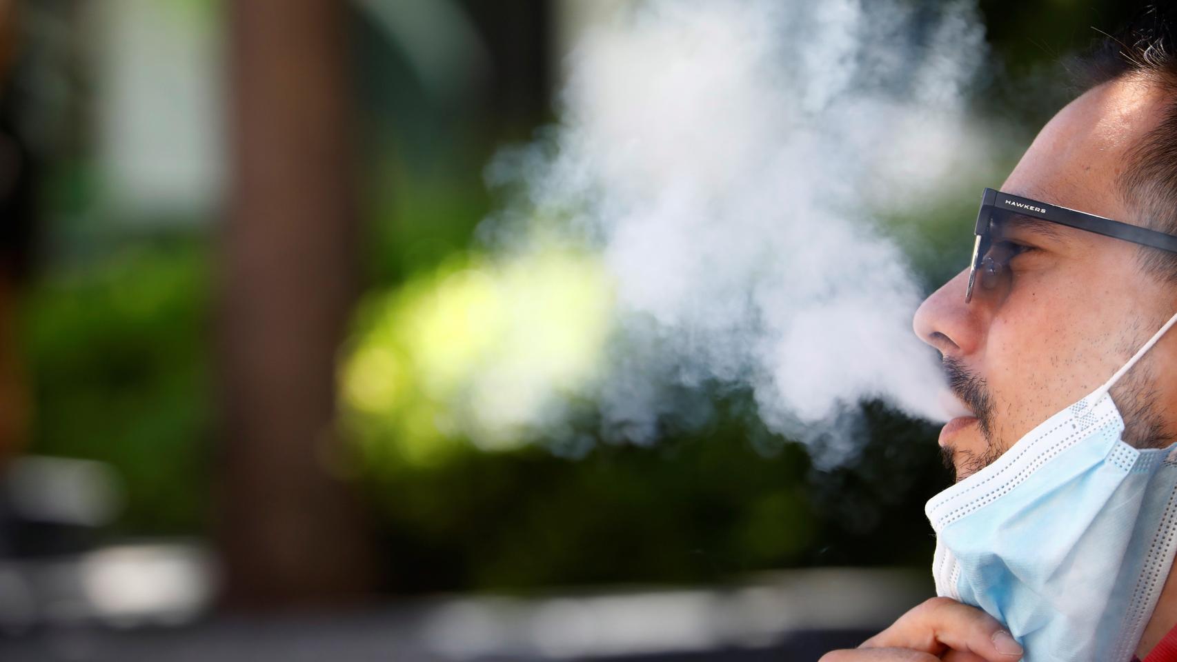 Un hombre, fumando en la vía pública.