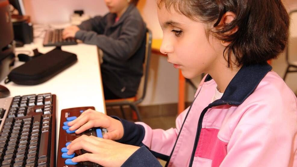 Niña ciega con ordenador en el aula