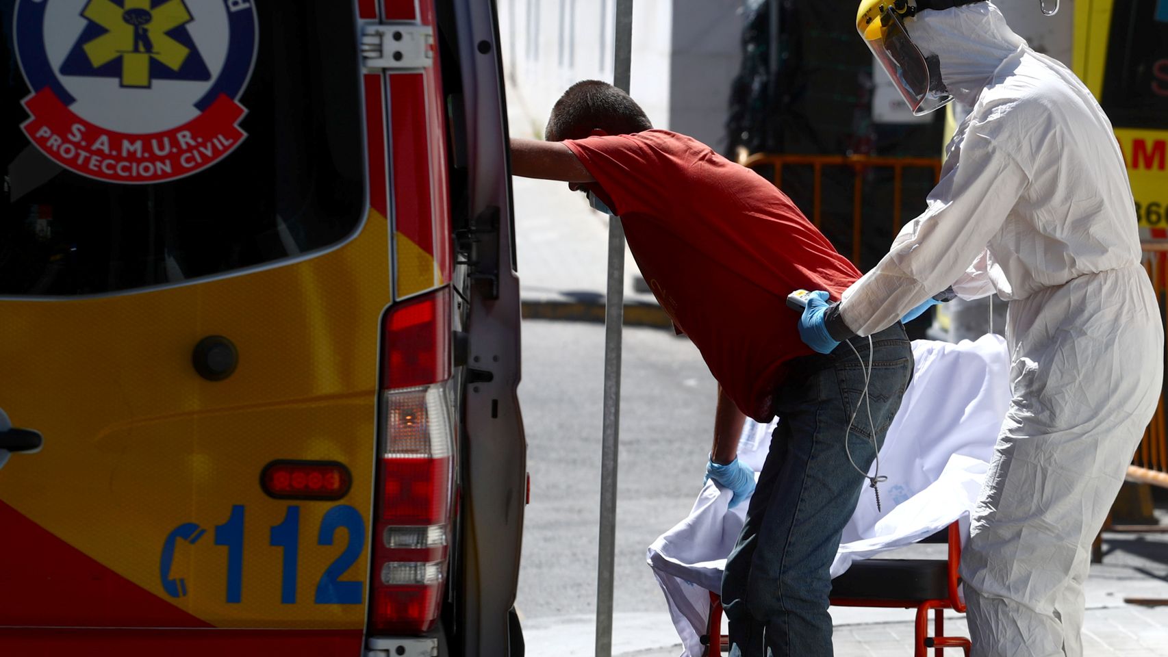 Un trabajador de Hospital 12 de Octubre equipado frente a la Covid ayuda a un paciente.