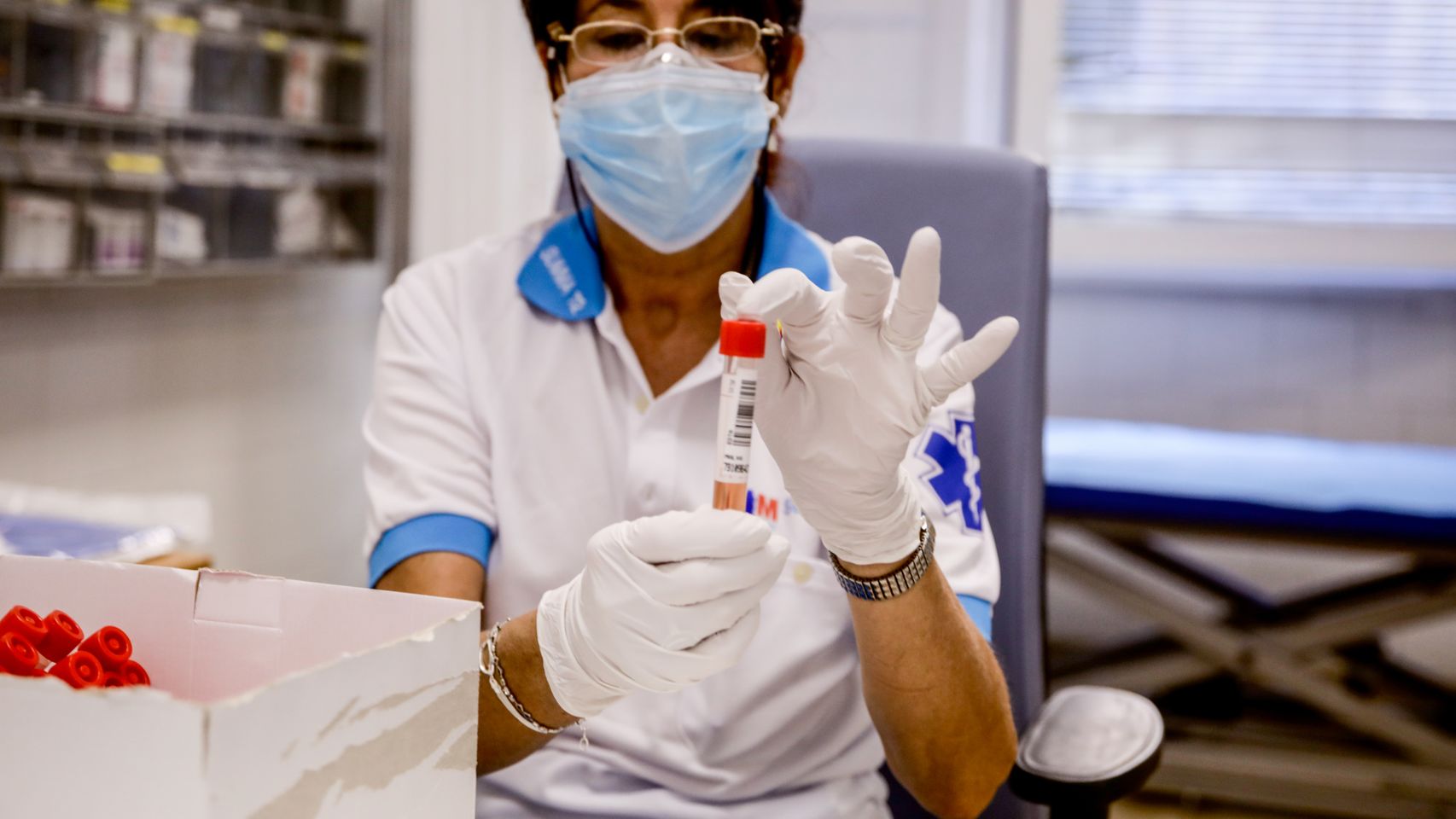 Una trabajadora sanitaria protegida sostiene una de las probetas utilizadas para la realización de PCR.