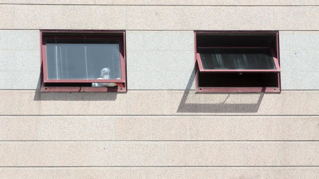 Un trabajador protegido es visto por uno de los cristales de la residencia de mayores DomusVi de Outeiro de Rei en Lugo.