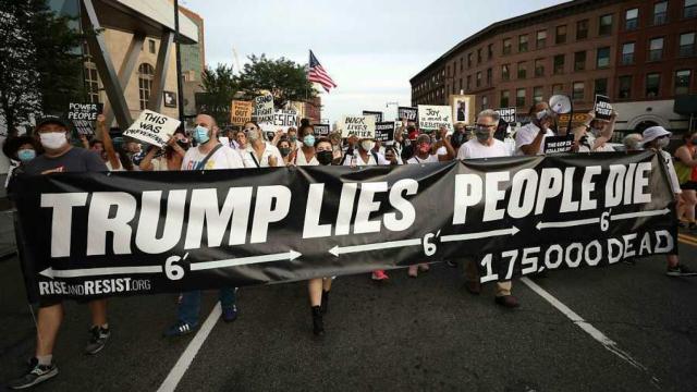 Personas marchan a la vigilia por las víctimas de la pandemia de coronavirus en Brooklyn, en agosto, con una pancarta que dice Trump miente, la gente muere.