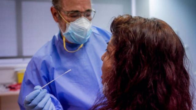 Un sanitario realiza una prueba PCR a una paciente.