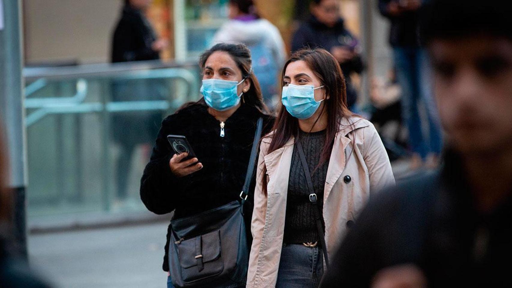 Dos mujeres pasean por la calle con mascarillas.