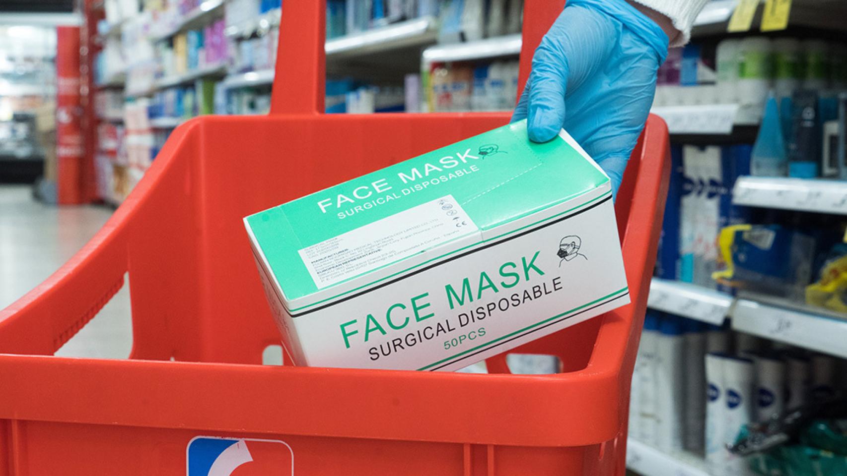 Una persona adquiere un paquete de mascarillas en un supermercado Eroski.