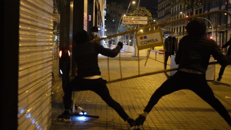 Dos hombres lanzan una valla contra un escaparate en Barcelona.