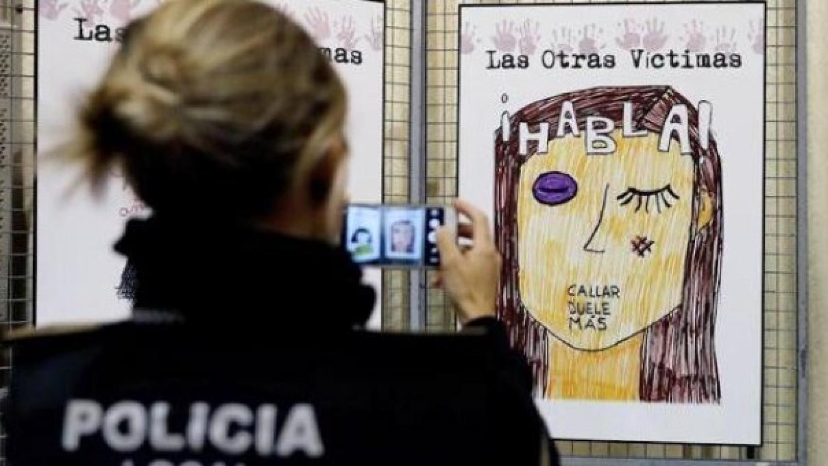 Una agente de la Policía Local fotografía un cartel contra la violencia machista.