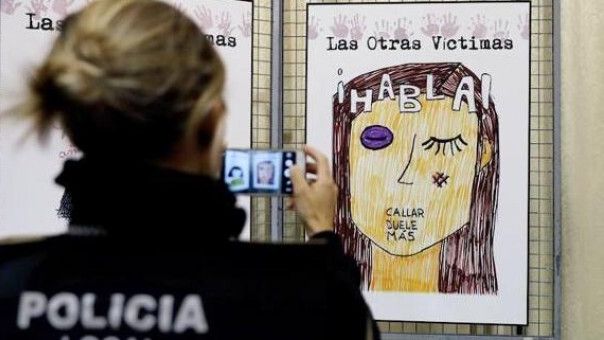 Una agente de la Policía Local fotografía un cartel contra la violencia machista.