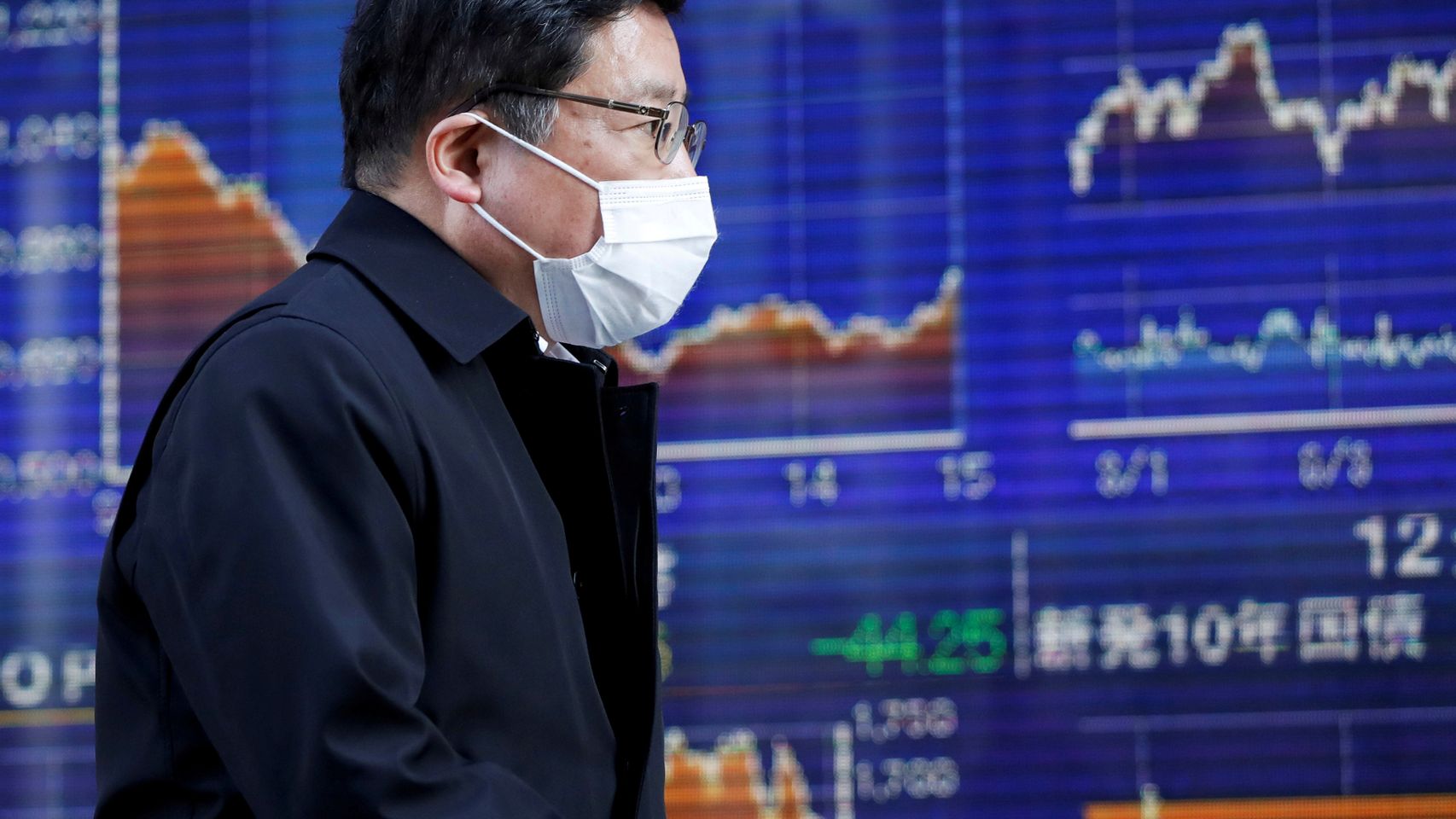 Un bróker pasa por delante de unas pantallas de negociación en la Bolsa de Tokio.