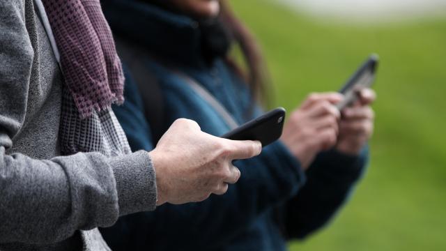 Dos personas usando su teléfono móvil.