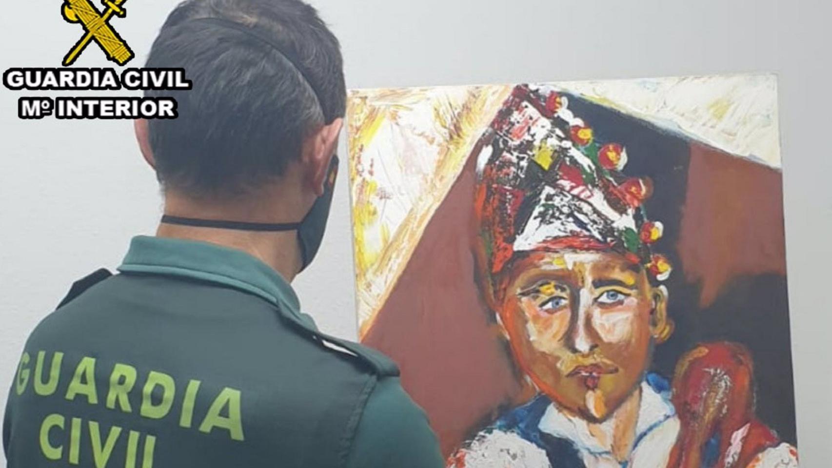 Agente de la Guardia Civil con un cuadro atribuido falsamente a un pintor gallego.