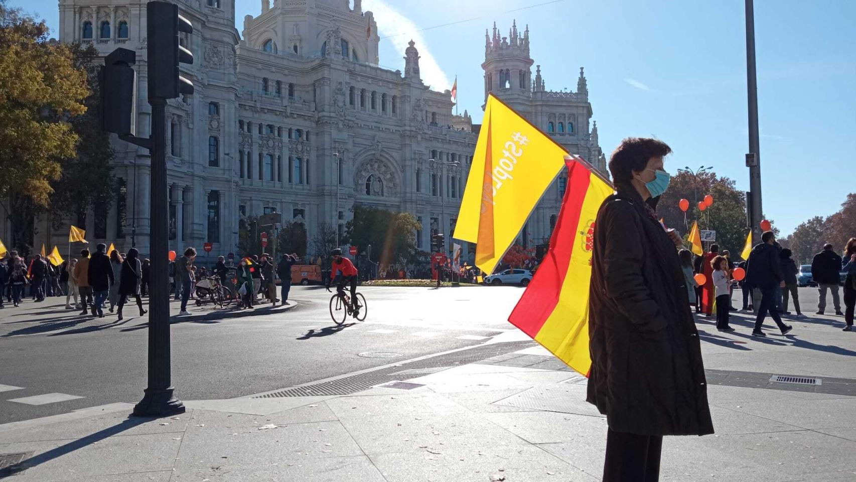 Una mujer ante el Ayuntamiento de Madrid, porta una bandera de España y una baderola contra la Ley Celaá.