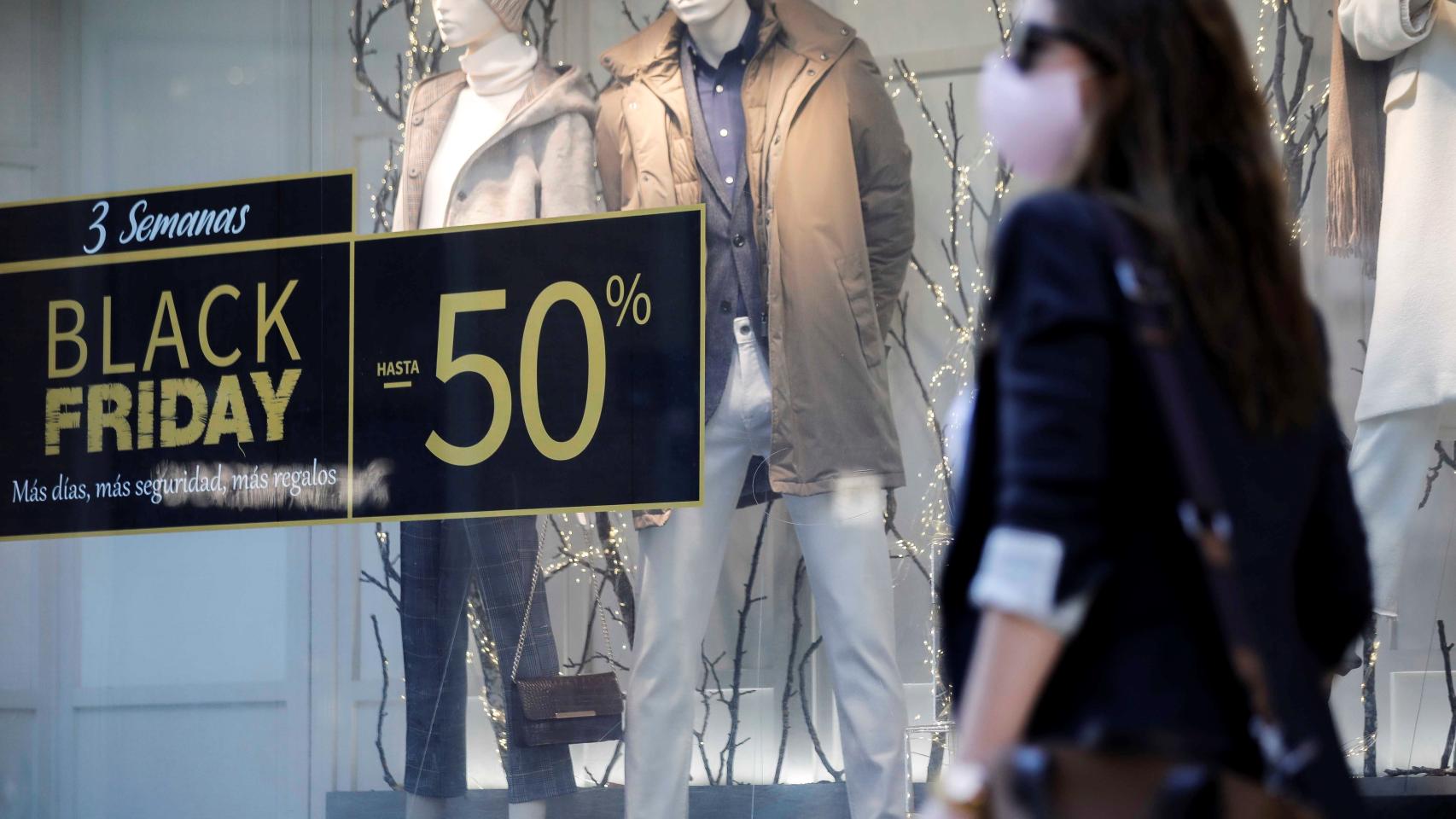 Una persona pasa ante un escaparate de un comercio con promociones.