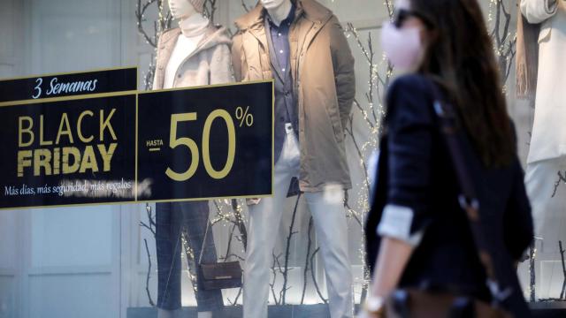 Una persona pasa ante un escaparate de un comercio con promociones.