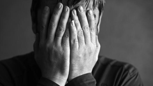 Un hombre se tapa la cara con las manos