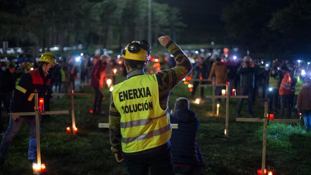 Un trabajador levanta el brazo como signo de protesta durante un velatorio nocturno simbólico.