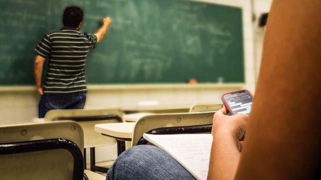 Un alumno consulta el móvil durante una clase.